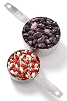 Two measuring cups with kidney beans, white background