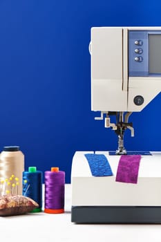 Spools of threads next to sewing machine on deep blue background