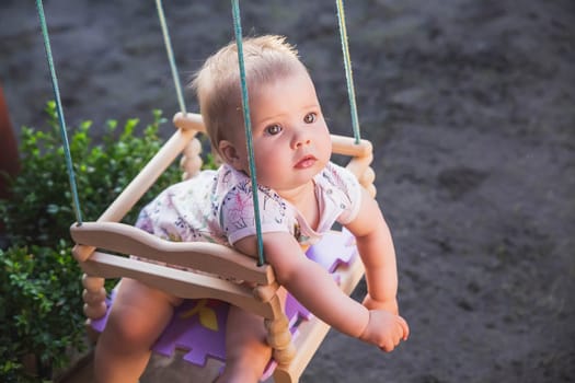 beautiful baby swinging in the yard on a children's swing sticking