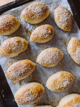 Freshly baked sesame buns lie on a baking sheet