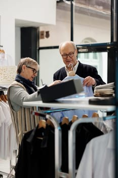 Senior couple looking at blue trendy shirt analyzing material
