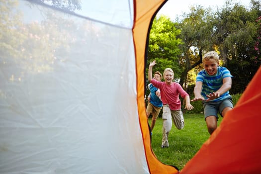 Loser sleeps outside. Full length shot of three young boys running into their tent.