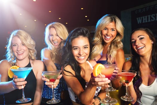 Making the most of ladies night. young women drinking cocktails in a nightclub.