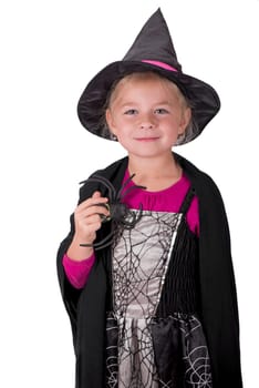 A beautiful girl in a witch costume, in a hat, with a spider in her hands on a light background, copy space. The witch waves her magic wand. Happy Halloween.