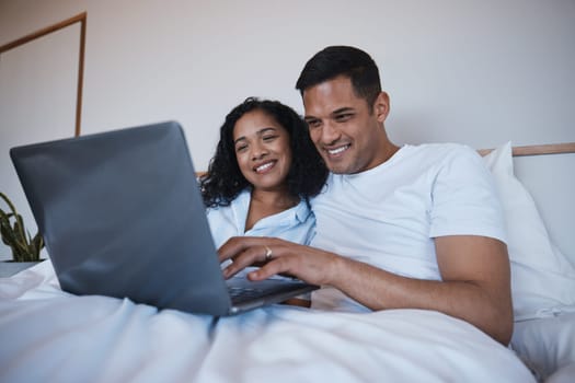 Love, laptop and happy couple relax in bed, bonding and enjoying streaming, movie or browsing in their home. Online, film and man with woman in a bedroom for weekend, entertainment and subscription