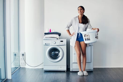 I never skip wash day. a young attractive woman doing her laundry at home.
