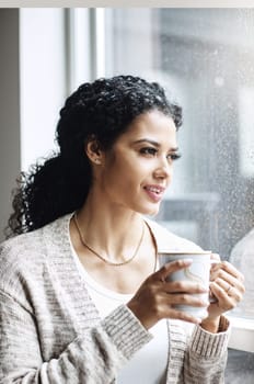 Its perfect weather to do nothing but relax at home. an attractive young woman relaxing at home with a cup of coffee