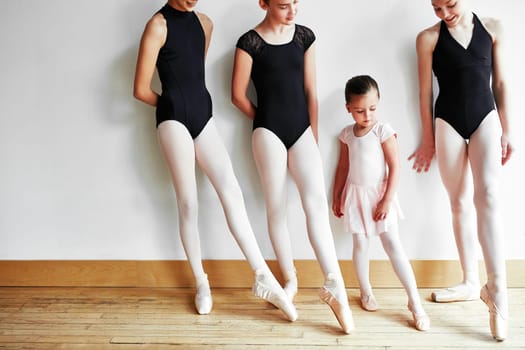 Shes got big ballet shoes to fill. a group of young ballerinas teaching a little girl ballet in a dance studio.