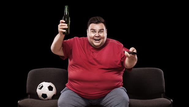 Soccer fun - happy and fat man watching tv, taking beer and soccer ball on black background.