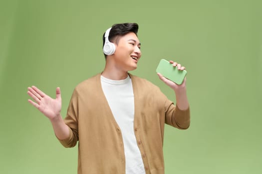 Young handsome man singing his favorite song, using a smartphone as a microphone, 