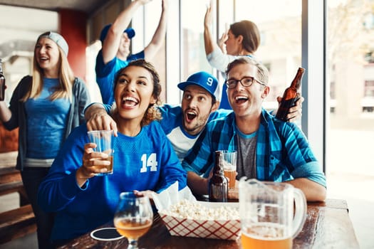 The atmosphere is electric. a group of friends cheering while watching a sports game at a bar.