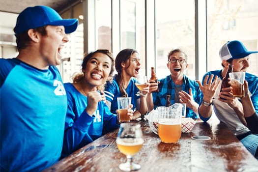 Sport has the unique power to unite people. a group of friends having beers while watching a sports game at a bar.