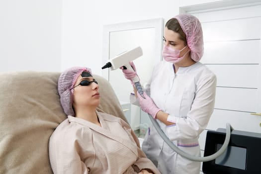 Carbon peeling in beauty salon. Cosmetologist performing carbon peeling to a young woman