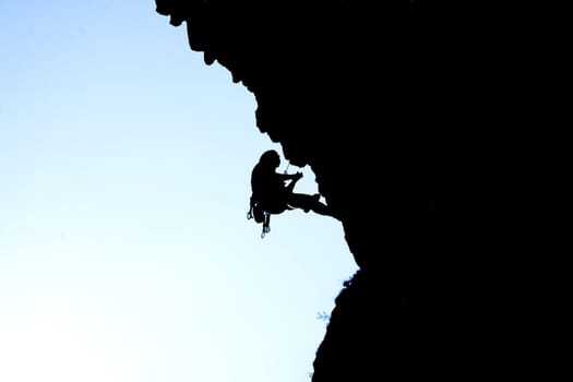 Person is climbing in the mountains, black silhouette.