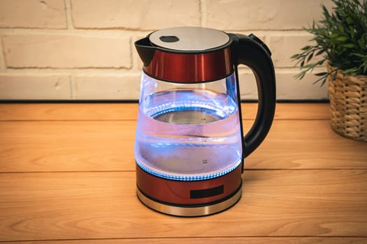 red modern boiling glass electric kettle close-up with bubbling water