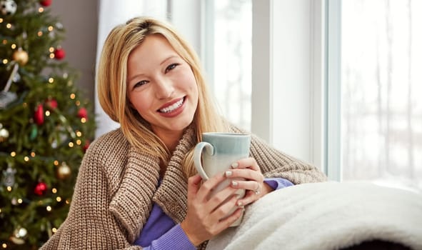 Coffee is the best company. a young woman relaxing at home with a cup of coffee.