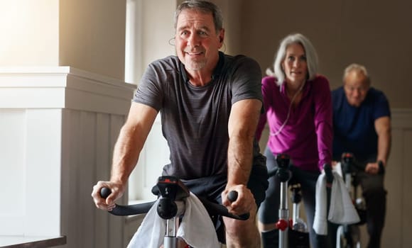 My fitness routine allows me to age so well. a group of seniors having a spinning class at the gym.