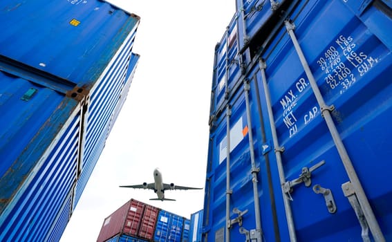 Airplane flying above container logistic. Cargo and shipping business. Container ship for import and export logistic. Logistic industry from port to port. Container at harbor for truck transport.