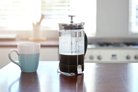 Start your morning right. a mug and french press on a kitchen counter.