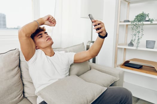 man interior curly mockup using adult freelancer modern mobile home couch sofa person cellphone cell male selfies smile smart cyberspace blissful