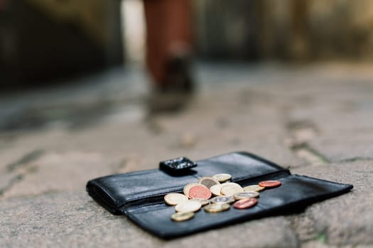 Photo of the sidewalk and legs of a man who lost a black leather wallet while walking