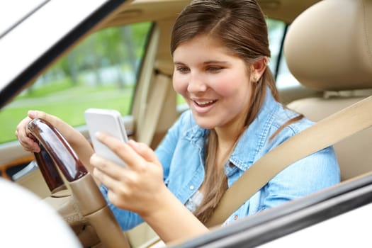 Eyes of the road - Dangerous Driving. A young girl taking her eyes off of the road to send a text message.