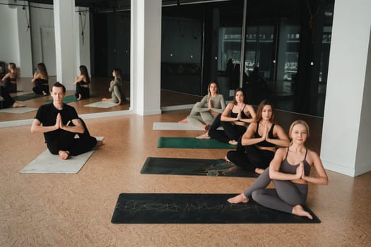 a group of girls do yoga in the gym under the guidance of a coach