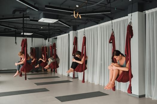 A group of women play sports on hanging hammocks. Fly yoga in the gym