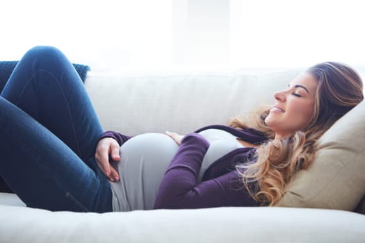Sleep is important for baby. an attractive young pregnant woman taking a nap on the sofa at home.