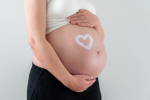 White drawing of a heart shape on a pregnant woman belly