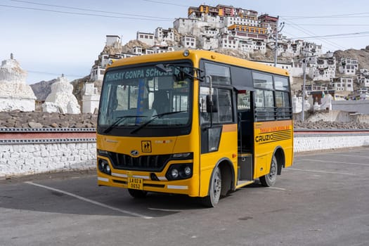 Thiksey, Ladakh, India - April 03, 2023: A yellow school bus parked in front of Thiksey monastery