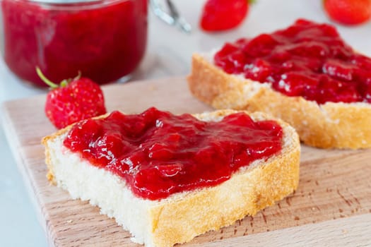 Wheat bread toasts with spread strawberry jam on the table