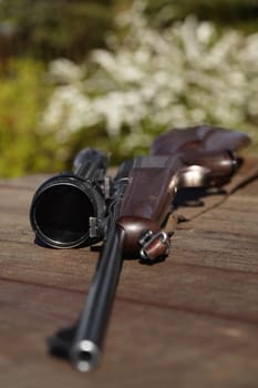 Hunting, rifle and weapon with a gun on a table outdoor in nature on a game reserve or blurred background. Sports, scope and sniper with hunter or military equipment on a wooden surface outside