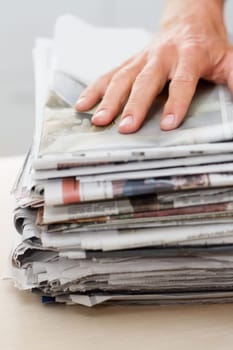 Newspaper, sustainability and hand of man on stack for recycling, environment and resources. Eco friendly, waste and news with closeup of person and paper for responsibility, garbage and conservation