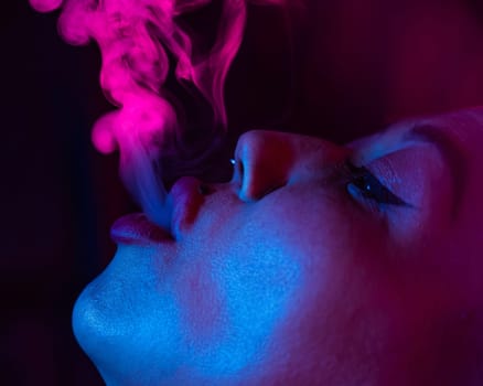 Close up portrait of asian woman with short hair smoking in neon light.