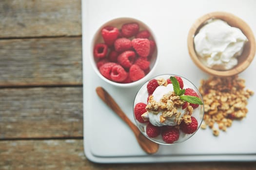 Start your morning the wholesome way. of granola, yoghurt and berries in a glass and on a plate.