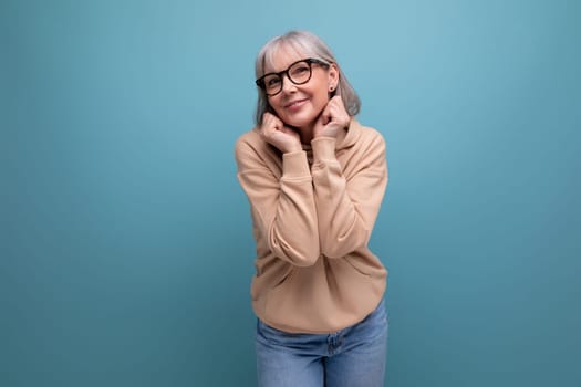 a middle-aged woman in a youth outfit flaunts on a studio background with copy space