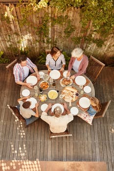 Family gatherings help them reconnect as a family. High angle shot of a family eating lunch outdoors.