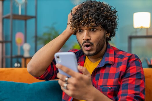 Sad indian man use smartphone surprised by bad news, fortune loss, fail, lottery results, deadline