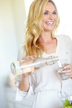 Staying healthy and hydrated. Attractive young blonde woman pouring herself a glass of water.