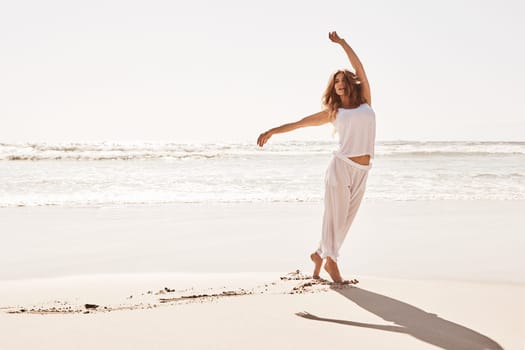 As carefree as can be. a young woman standing with her arms outstretched at the beach.