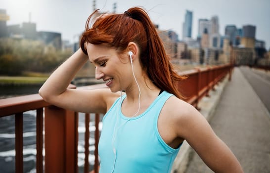 Fitness is a good feeling. a sporty young woman listening to music while out for a run in the city.