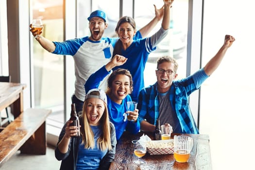 We always get together when its match day. a group of friends cheering while watching a sports game at a bar