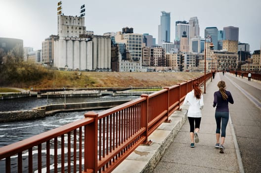 Fitness is their destination. Rearview shot of two unrecognizable young women running through the city.