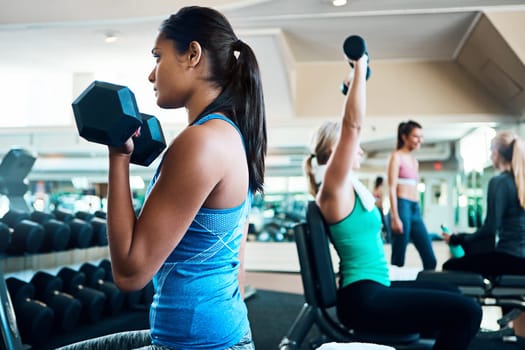 Lift your game. attractive young women working out with dumbbells at the gym.