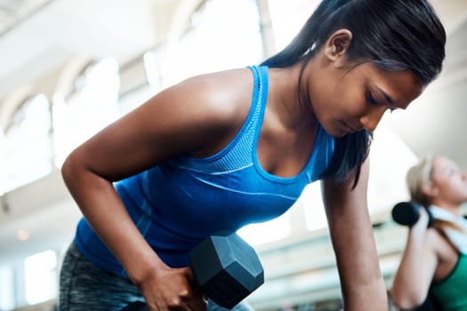 Her arms are full of strength. attractive young women working out with dumbbells at the gym.