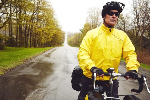 Never let the weather stop you. a male cyclist enjoying a bike ride on a wet winters morning
