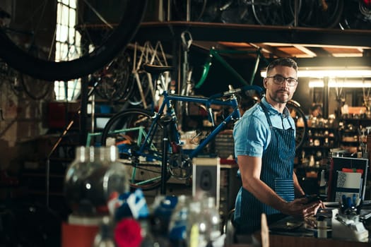 Your one stop bicycle repair shop. Portrait of a mature man working in a bicycle repair shop.