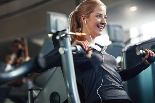 Exercise is a great mood booster. a young woman working out with a chest press at a gym.