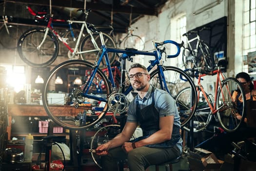 Specializing in anything bicycle related. Portrait of a mature man working in a bicycle repair shop with his coworker in the background.
